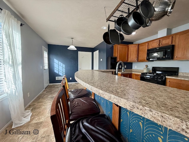 kitchen with a kitchen bar, brown cabinets, black appliances, light countertops, and baseboards