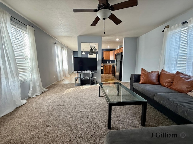 living area with light carpet, baseboards, and a ceiling fan