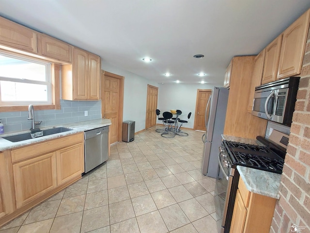 kitchen with light tile patterned flooring, a sink, light brown cabinetry, appliances with stainless steel finishes, and tasteful backsplash