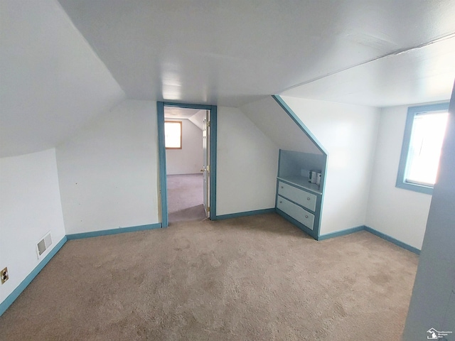 additional living space with vaulted ceiling, carpet, visible vents, and baseboards