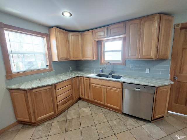 kitchen with dishwasher, light stone counters, backsplash, and a sink