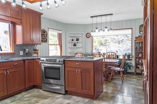 kitchen with a peninsula, a sink, pendant lighting, gas range, and tasteful backsplash