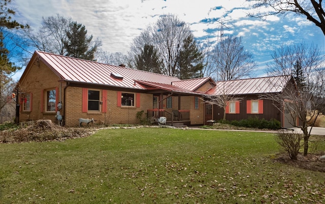 back of house with a standing seam roof, a yard, brick siding, and metal roof