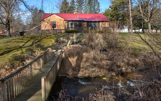 back of property with metal roof and fence