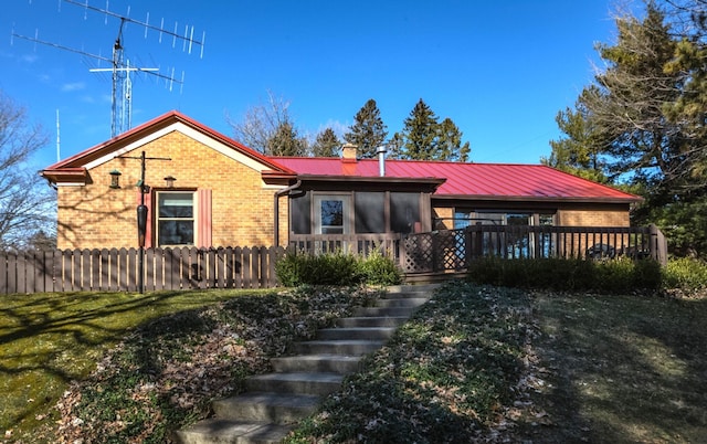 view of front of house with stairs, fence, brick siding, and metal roof