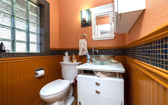 half bath featuring vanity, toilet, and wainscoting