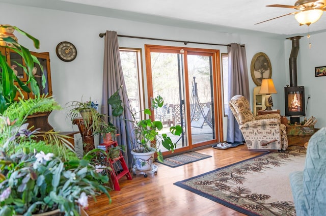 entrance foyer with a wood stove, wood finished floors, and a ceiling fan