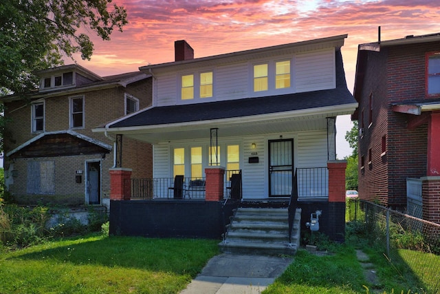 traditional style home featuring a yard, a porch, a chimney, and fence