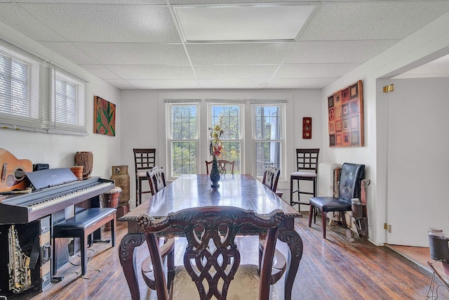 dining area with wood finished floors and a paneled ceiling