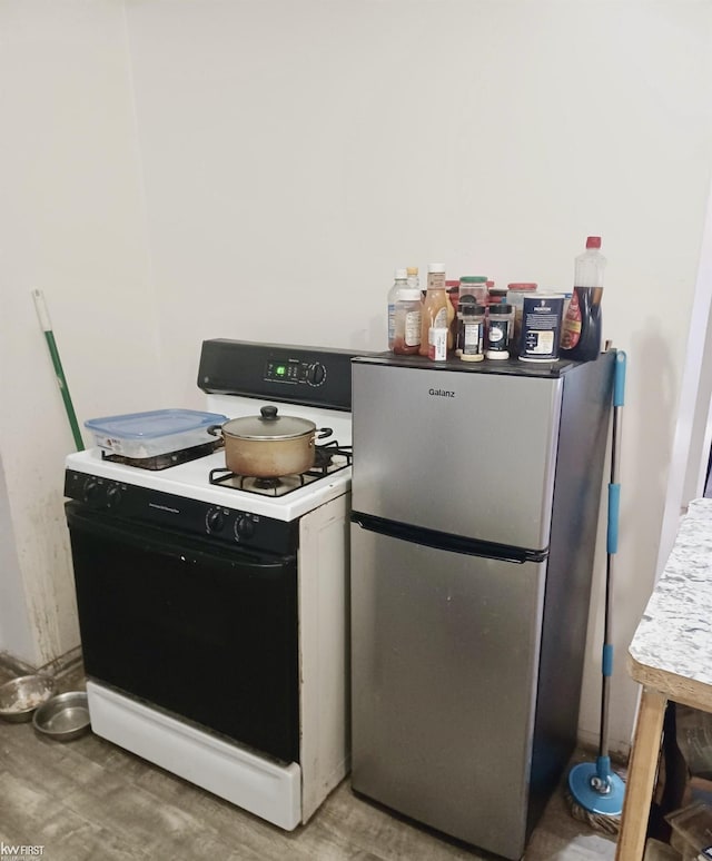 kitchen with light countertops, freestanding refrigerator, and gas range oven