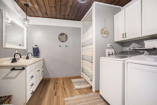 laundry area featuring cabinet space, a sink, wooden ceiling, light wood-type flooring, and washer and clothes dryer