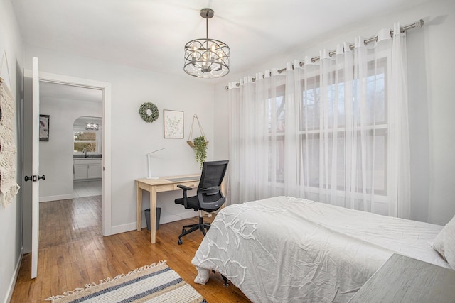 bedroom featuring a sink, baseboards, a chandelier, and hardwood / wood-style flooring