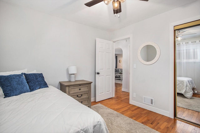 bedroom featuring visible vents, baseboards, a closet, hardwood / wood-style floors, and arched walkways