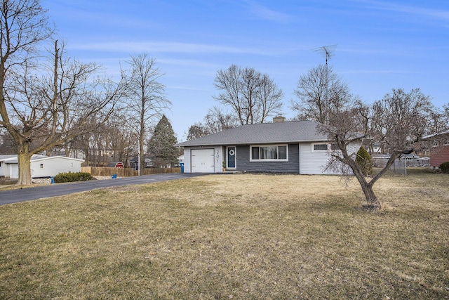 single story home with aphalt driveway, an attached garage, a front lawn, and a chimney