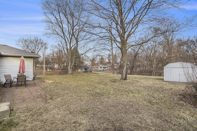 view of yard with an outbuilding, a shed, a patio area, and fence