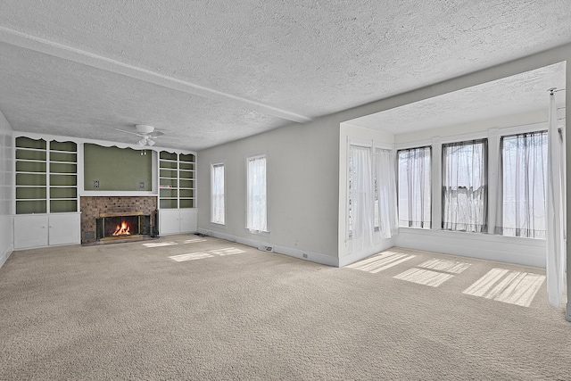 unfurnished living room with a brick fireplace, carpet flooring, a ceiling fan, and a textured ceiling