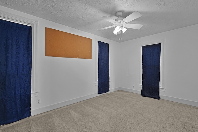 carpeted empty room with baseboards, a textured ceiling, and ceiling fan