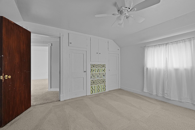 unfurnished bedroom featuring vaulted ceiling, carpet, a closet, and ceiling fan