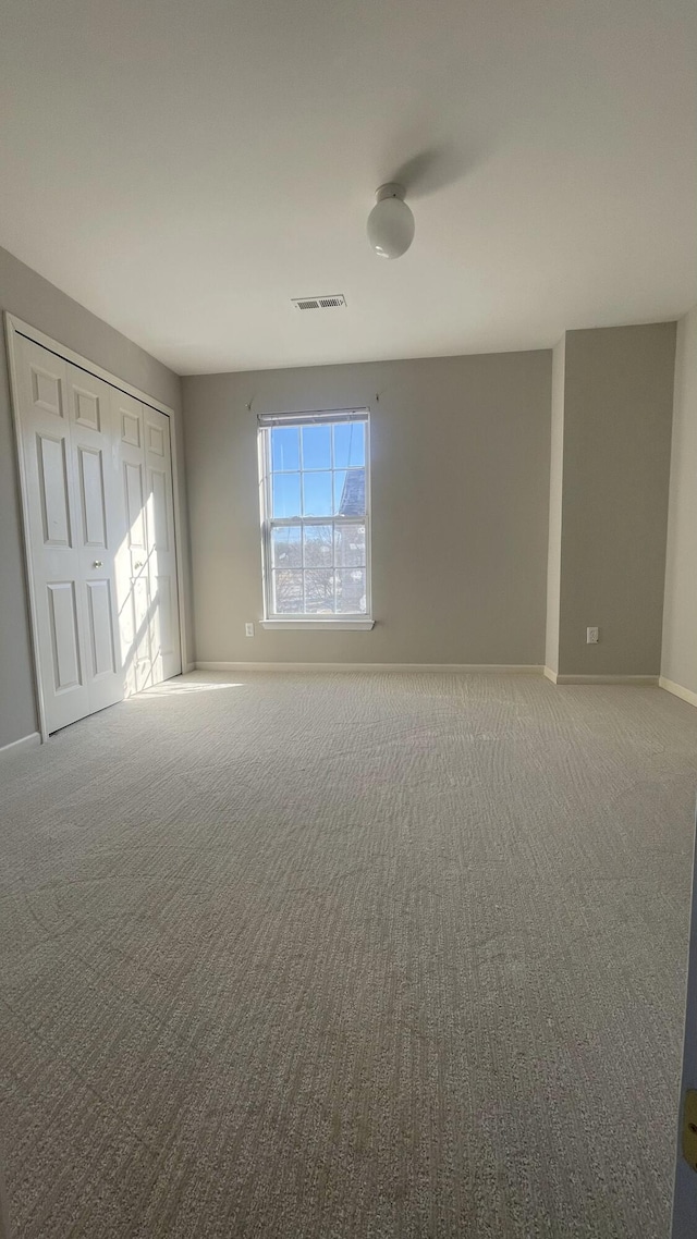 empty room with visible vents, carpet floors, and baseboards