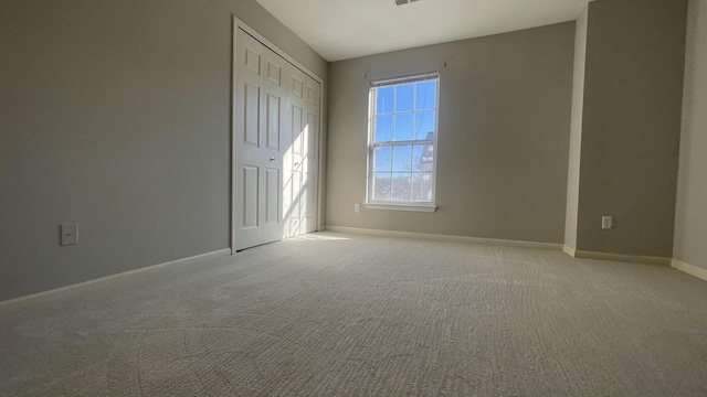 spare room featuring light carpet and baseboards