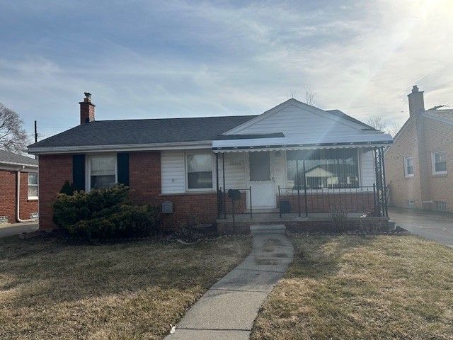 view of front of house featuring a front lawn, brick siding, and a chimney