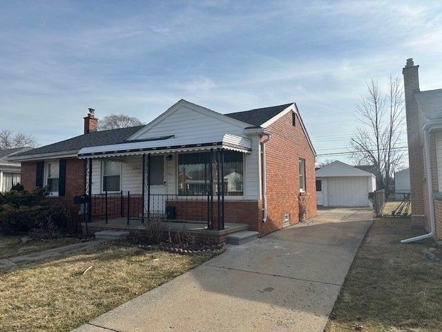 bungalow-style home with a garage, brick siding, a porch, and a chimney