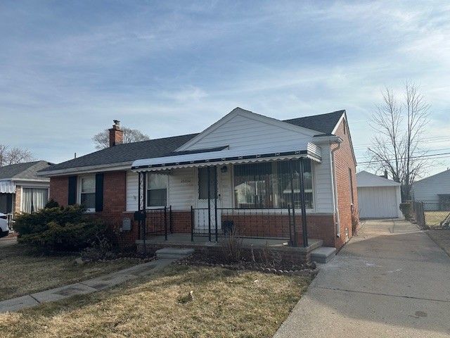 view of front of home featuring a porch, brick siding, a front yard, and a chimney