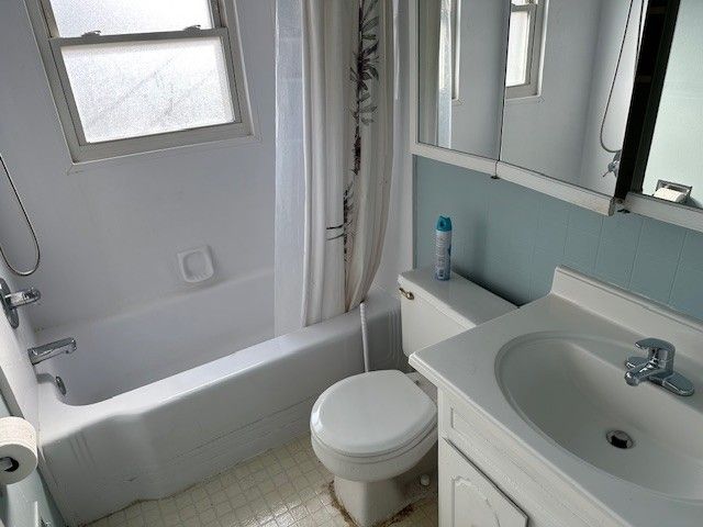 bathroom featuring a wealth of natural light, toilet, vanity, and shower / bath combination with curtain