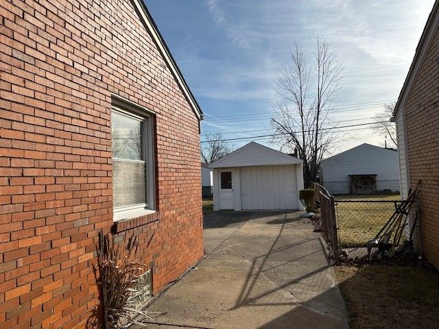 view of home's exterior with an outbuilding, brick siding, and fence