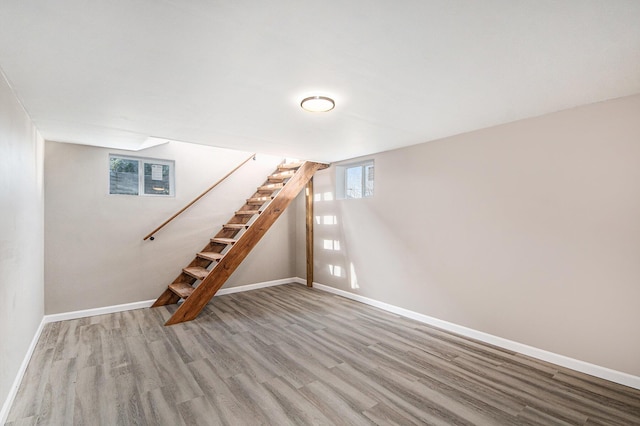 below grade area featuring stairway, baseboards, and wood finished floors