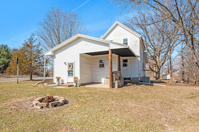 rear view of house with a yard, cooling unit, and an outdoor fire pit