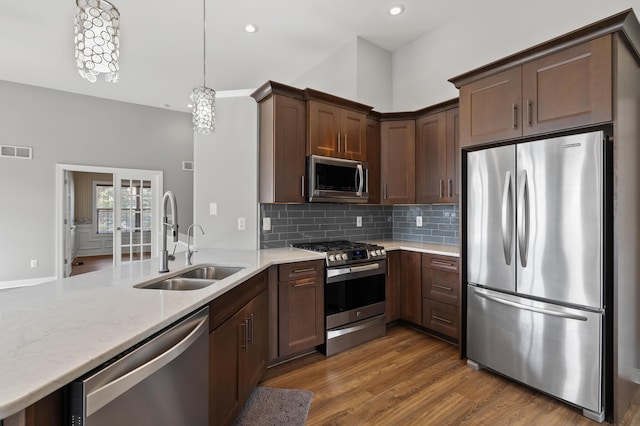 kitchen with visible vents, a sink, wood finished floors, appliances with stainless steel finishes, and a peninsula