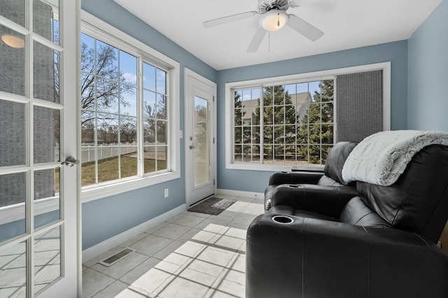 interior space with light tile patterned floors, visible vents, a ceiling fan, and baseboards