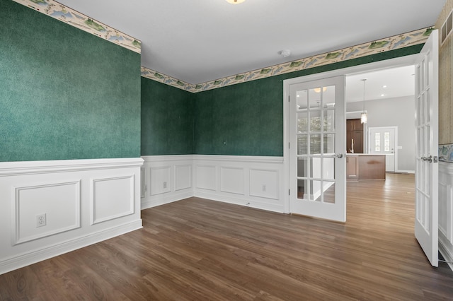 empty room with a wainscoted wall, wood finished floors, and wallpapered walls