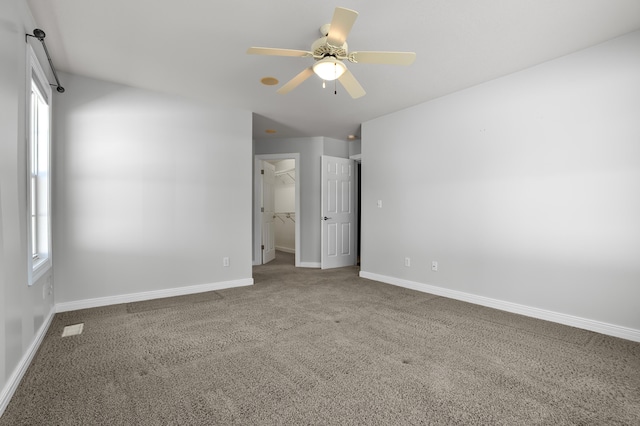 unfurnished bedroom with a walk in closet, carpet flooring, visible vents, and baseboards