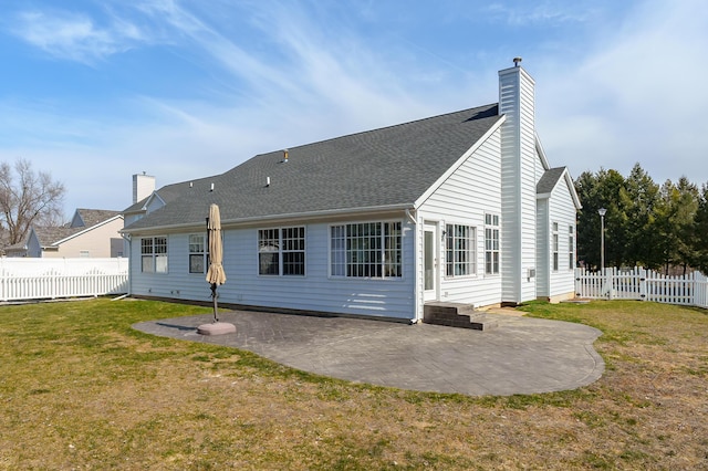 rear view of house featuring a patio, a lawn, a fenced backyard, and a chimney