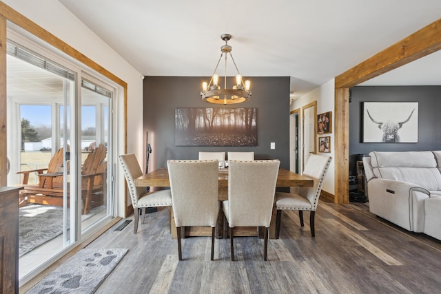 dining room featuring an inviting chandelier, beamed ceiling, wood finished floors, and baseboards