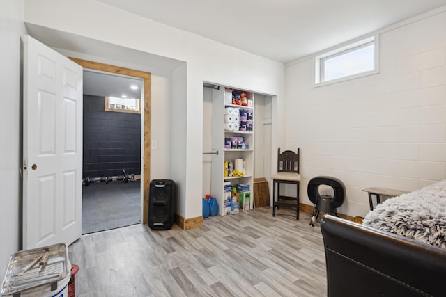 bedroom featuring light wood finished floors and concrete block wall