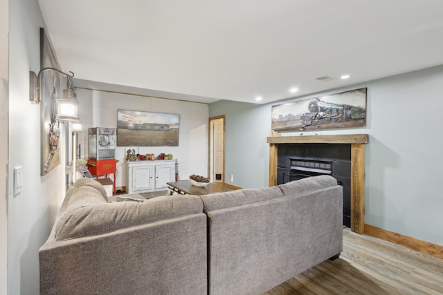 living area with wood finished floors, baseboards, visible vents, recessed lighting, and a fireplace