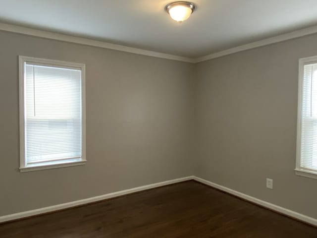 unfurnished room with dark wood-style floors, crown molding, and baseboards