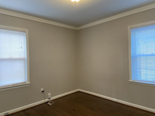 empty room featuring baseboards, dark wood-style floors, and crown molding