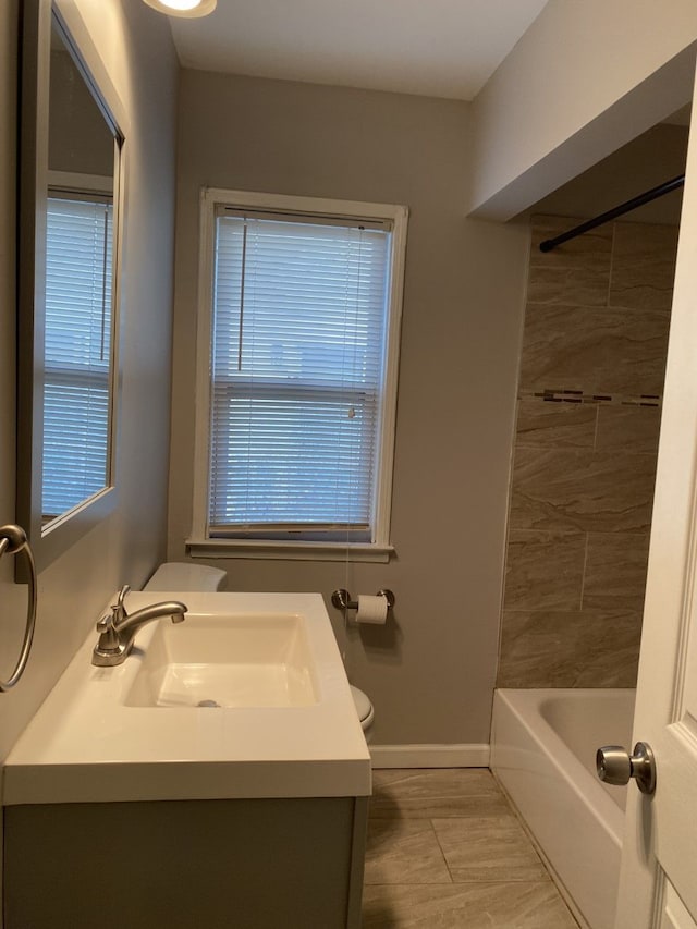 bathroom with baseboards, toilet, bathtub / shower combination, and vanity