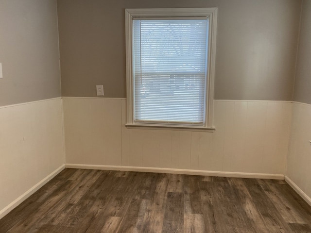 unfurnished room with dark wood-type flooring and wainscoting