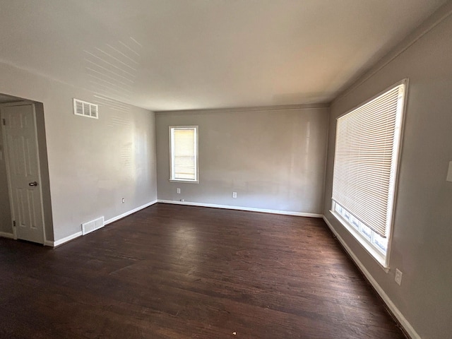 empty room with visible vents, baseboards, and dark wood-style flooring