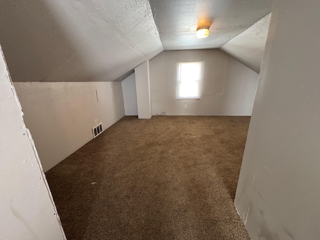 bonus room featuring vaulted ceiling, carpet flooring, visible vents, and a textured ceiling