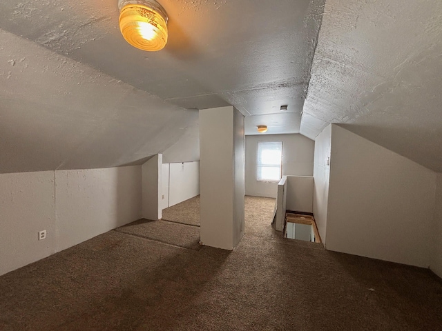 bonus room featuring a textured ceiling, vaulted ceiling, and carpet