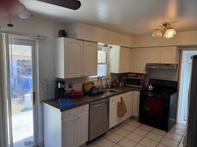 kitchen featuring a sink, stainless steel appliances, dark countertops, and white cabinetry