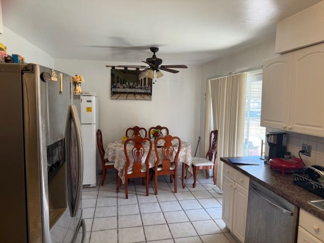 kitchen featuring a ceiling fan, dark countertops, appliances with stainless steel finishes, white cabinets, and decorative backsplash