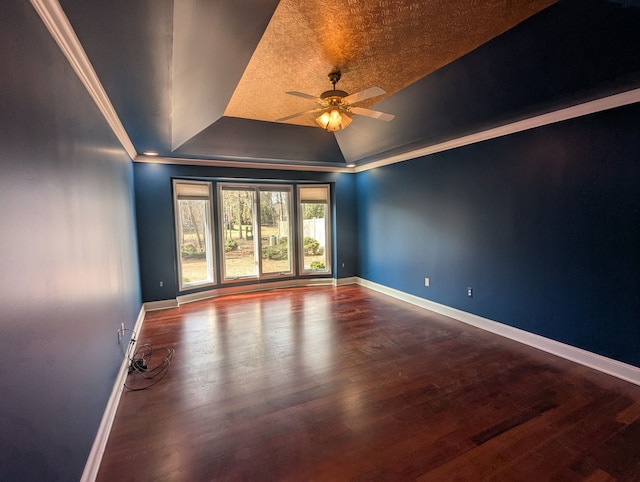 empty room featuring baseboards, a raised ceiling, a ceiling fan, and wood finished floors