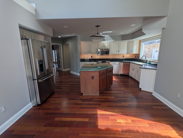 kitchen featuring dark wood-type flooring, a sink, backsplash, stainless steel appliances, and baseboards